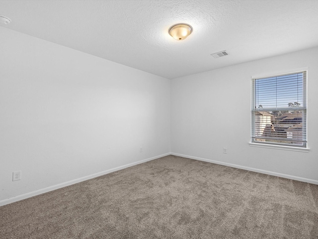 spare room featuring visible vents, carpet floors, a textured ceiling, and baseboards