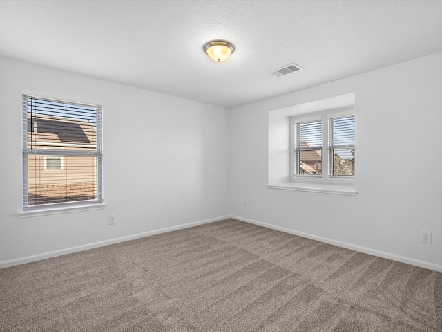 carpeted empty room with visible vents, baseboards, and a textured ceiling