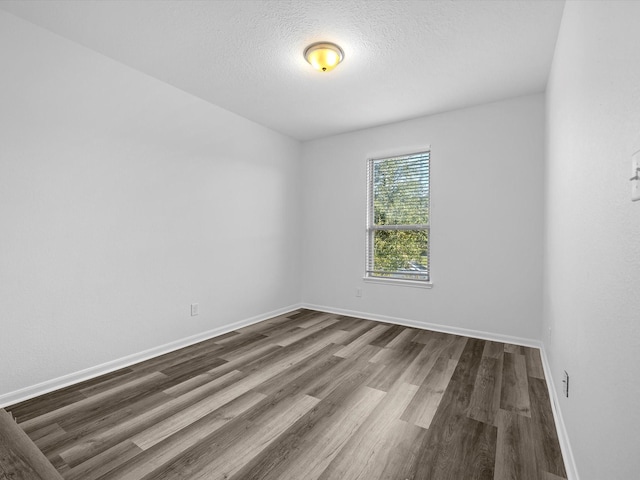 unfurnished room featuring baseboards, dark wood-type flooring, and a textured ceiling