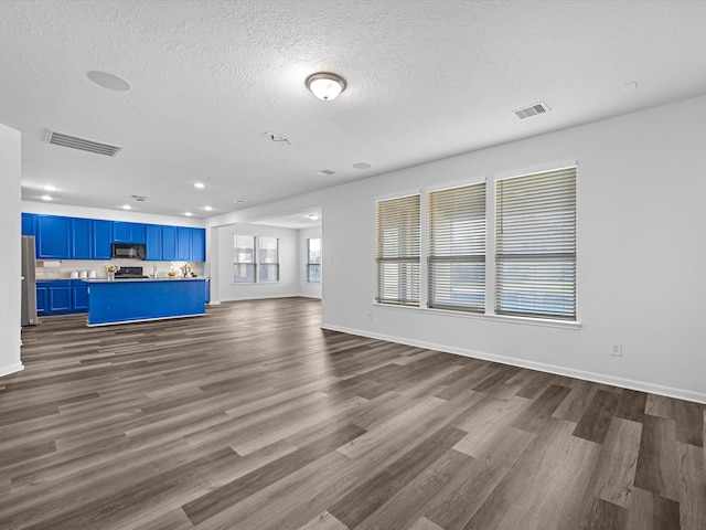 unfurnished living room featuring visible vents, a textured ceiling, and dark wood finished floors