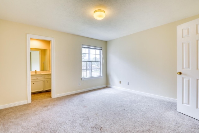 unfurnished bedroom with connected bathroom, baseboards, and carpet flooring