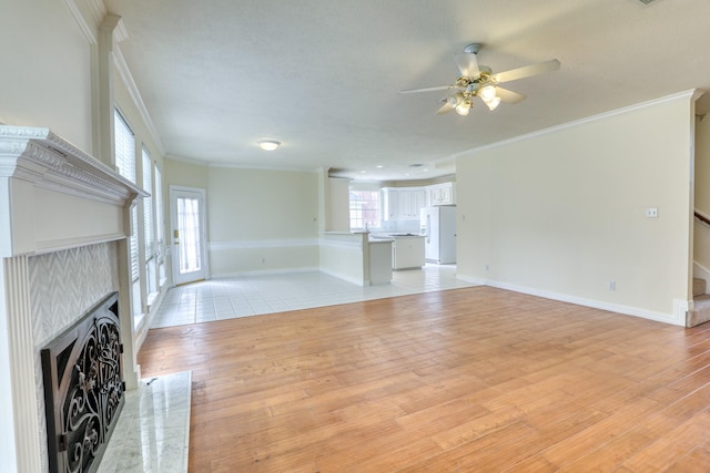 unfurnished living room with a fireplace with flush hearth, ornamental molding, stairway, light wood-style floors, and baseboards