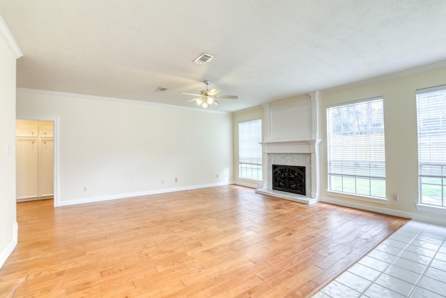 unfurnished living room with visible vents, ornamental molding, a high end fireplace, and light wood finished floors