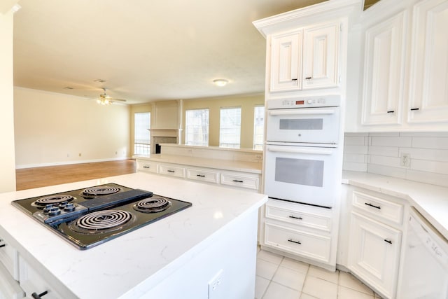 kitchen featuring a ceiling fan, light stone counters, open floor plan, white appliances, and decorative backsplash