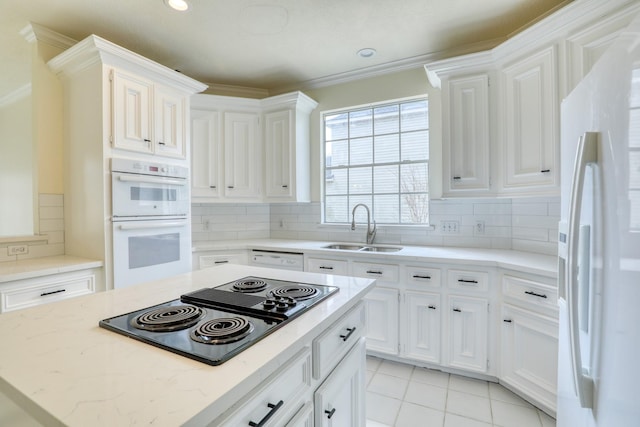 kitchen featuring tasteful backsplash, white appliances, white cabinetry, and a sink