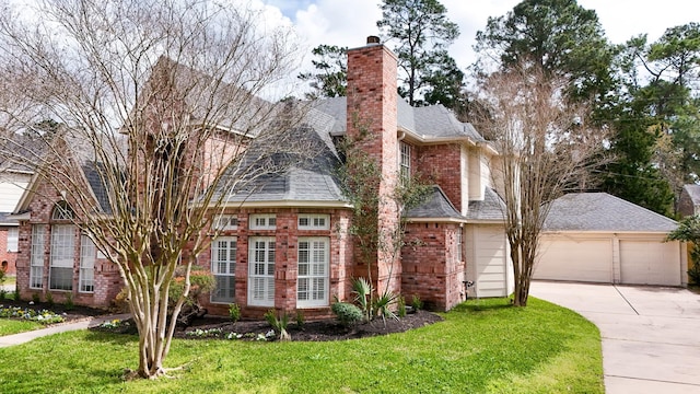 view of front of house featuring a front lawn, brick siding, concrete driveway, and a chimney