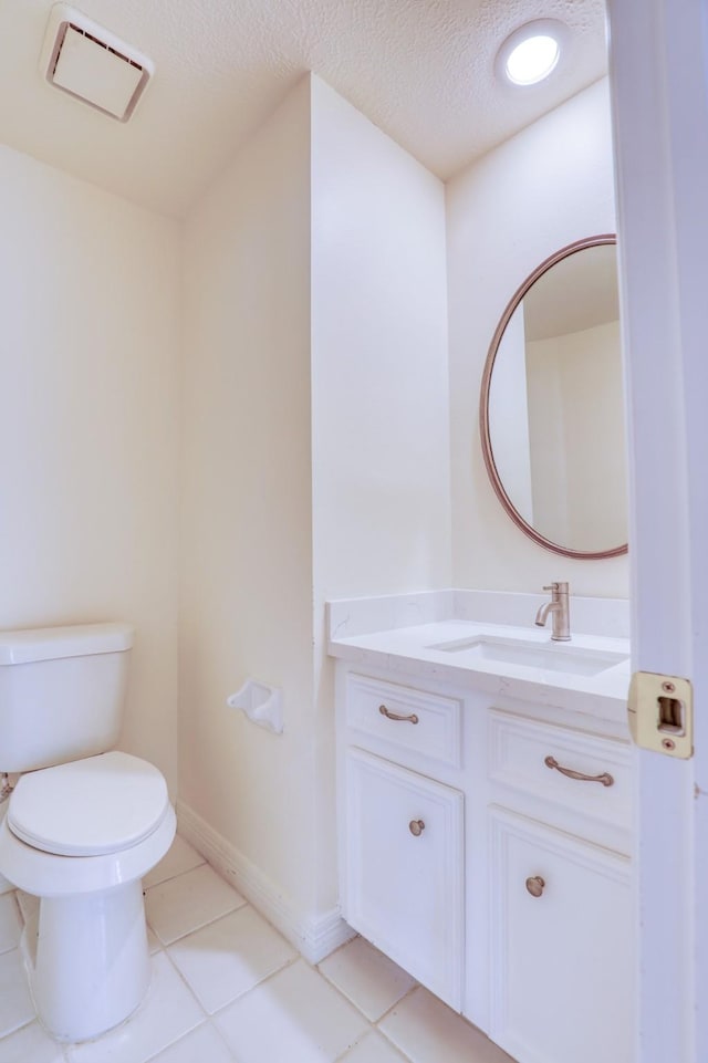 half bathroom featuring vanity, visible vents, tile patterned flooring, a textured ceiling, and toilet