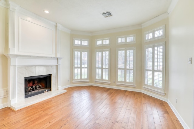 unfurnished living room featuring visible vents, crown molding, baseboards, light wood-type flooring, and a tile fireplace