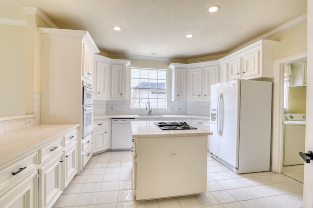 kitchen with white appliances, washer / clothes dryer, light countertops, and a sink