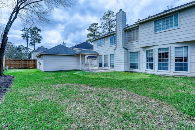 back of property featuring a patio area, a lawn, a chimney, and fence