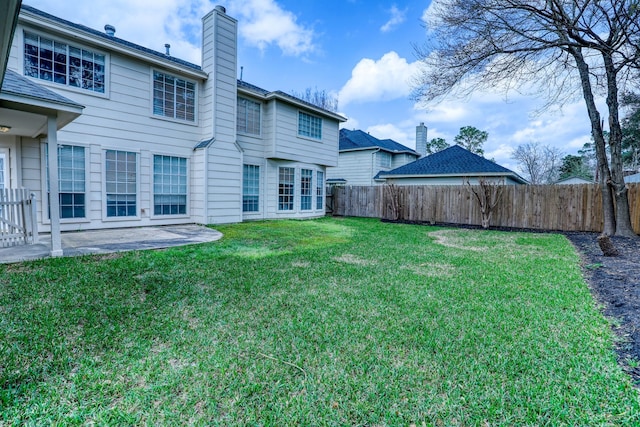 back of house featuring a patio, a yard, fence, and a chimney