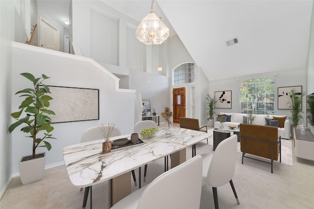 dining space featuring visible vents, a high ceiling, an inviting chandelier, light carpet, and baseboards