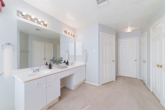 bathroom with double vanity, baseboards, visible vents, and a sink