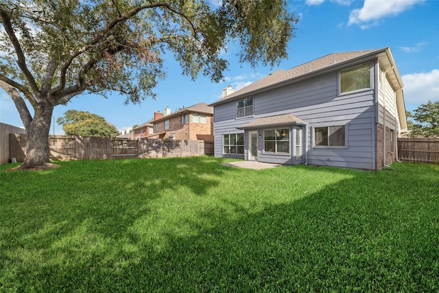 back of house with brick siding, a lawn, and a fenced backyard