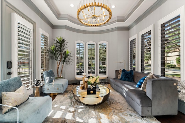 living area featuring a tray ceiling, crown molding, and an inviting chandelier