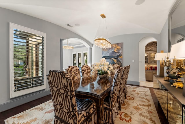5006 Water View Bnd, Sugar Land, TX 77479 - dining area featuring a chandelier, arched walkways, wood finished floors, vaulted ceiling, and baseboards