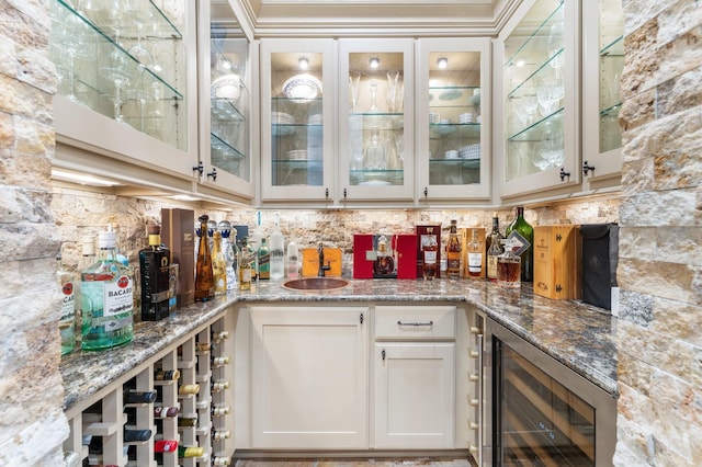 bar featuring a sink, wine cooler, backsplash, and indoor wet bar