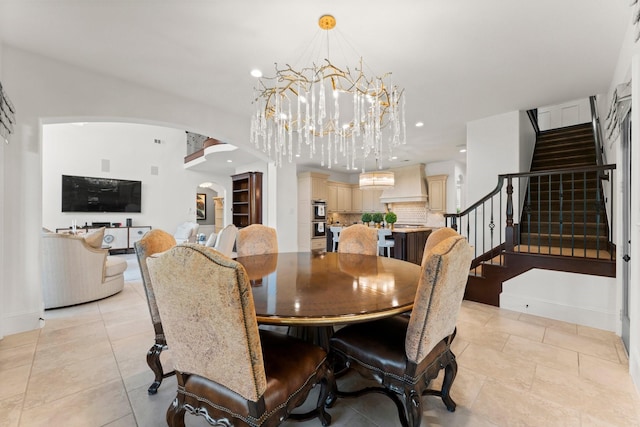 dining space with arched walkways, a notable chandelier, recessed lighting, baseboards, and stairs