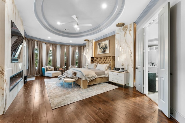 bedroom with dark wood-style flooring, recessed lighting, a raised ceiling, ornamental molding, and a high end fireplace