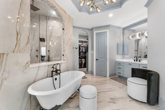 bathroom with a walk in closet, marble finish floor, crown molding, a freestanding bath, and vanity