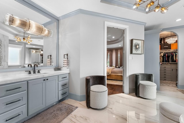 full bath with crown molding, a tray ceiling, a notable chandelier, and vanity