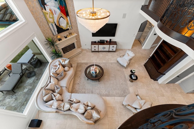 living room featuring a towering ceiling, a fireplace with raised hearth, and a notable chandelier