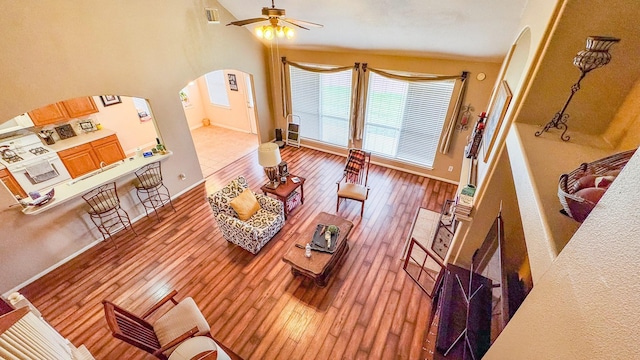 living area featuring a ceiling fan, arched walkways, visible vents, and hardwood / wood-style floors