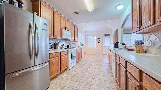 kitchen featuring light tile patterned floors, white appliances, a sink, light countertops, and backsplash