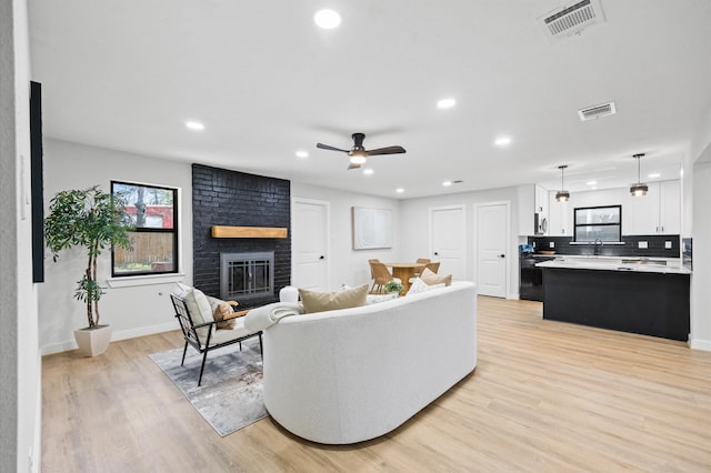 living room featuring a fireplace, visible vents, and light wood-type flooring