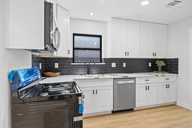 kitchen featuring visible vents, light wood-style flooring, a sink, appliances with stainless steel finishes, and light countertops