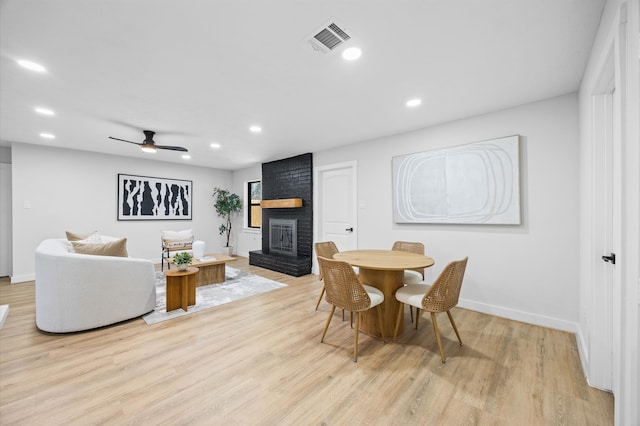 dining area with visible vents, recessed lighting, a brick fireplace, and light wood-type flooring