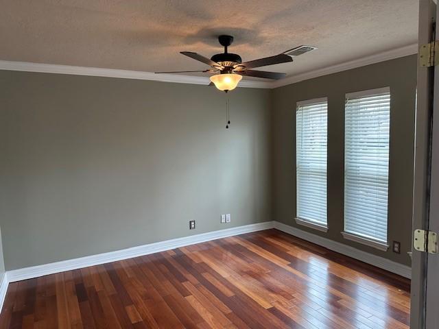 unfurnished room featuring a textured ceiling, ornamental molding, dark wood finished floors, and baseboards