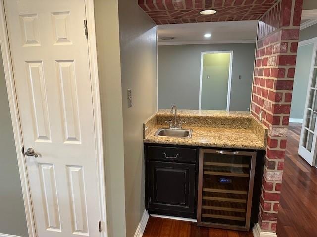 bar with beverage cooler, baseboards, a sink, crown molding, and indoor wet bar