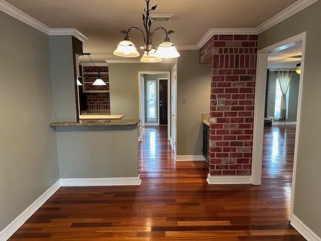 kitchen with a notable chandelier, hanging light fixtures, ornamental molding, wood finished floors, and baseboards