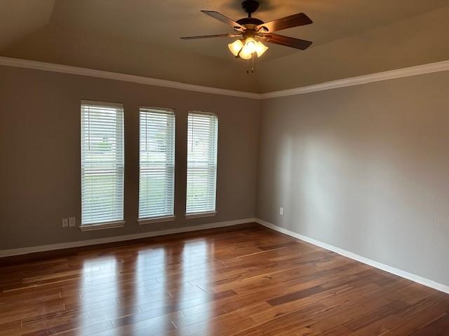 spare room featuring a ceiling fan, baseboards, ornamental molding, and wood finished floors