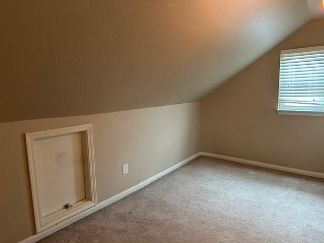 bonus room featuring lofted ceiling, baseboards, and carpet flooring