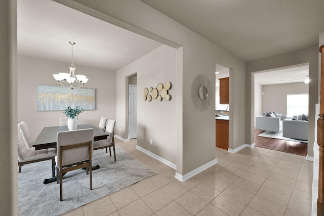 dining space with light tile patterned flooring, baseboards, and an inviting chandelier