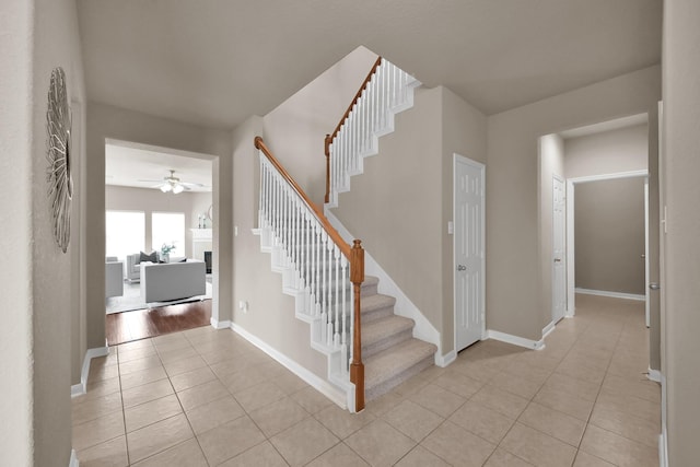 staircase with ceiling fan, tile patterned flooring, and baseboards