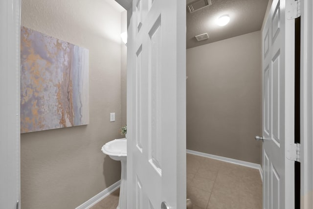 bathroom with baseboards, visible vents, a textured ceiling, and tile patterned floors