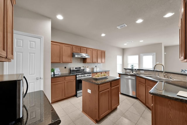 kitchen with decorative backsplash, a kitchen island, stainless steel appliances, under cabinet range hood, and a sink