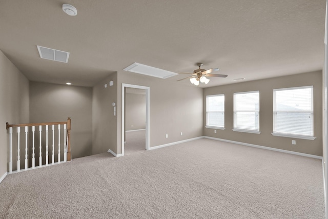 empty room with carpet floors, attic access, and baseboards