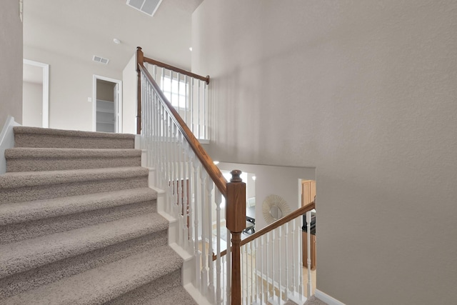 stairs featuring carpet floors, visible vents, and a high ceiling