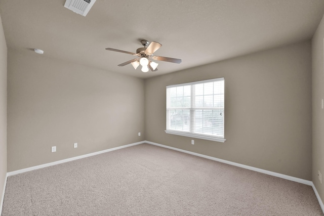 spare room with a ceiling fan, visible vents, carpet floors, and baseboards