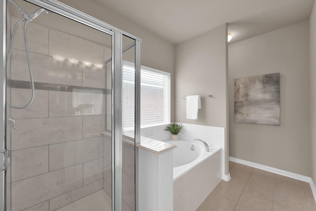 bathroom featuring a stall shower, tile patterned flooring, a bath, and baseboards