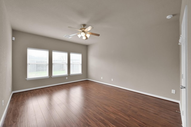 spare room featuring a ceiling fan, dark wood finished floors, and baseboards