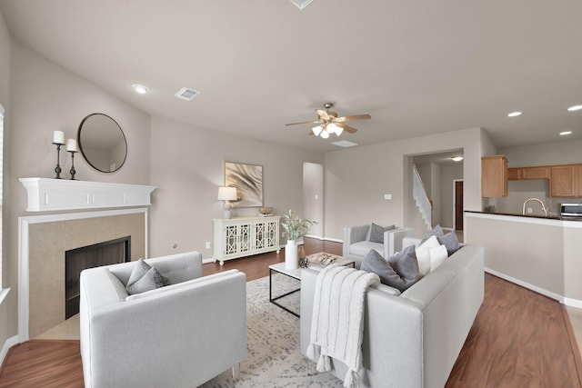 living area with a tile fireplace, visible vents, recessed lighting, and wood finished floors