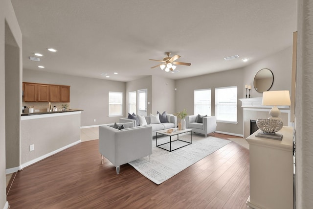 living area with a wealth of natural light, visible vents, a fireplace, and wood finished floors