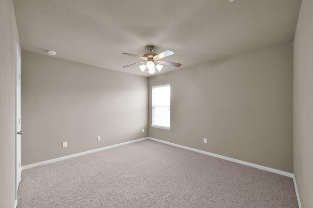 carpeted spare room featuring ceiling fan and baseboards