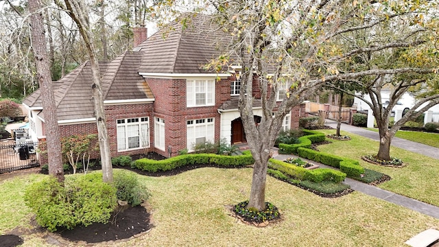 view of front of home featuring a chimney, a front yard, fence, and brick siding