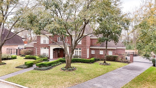 view of front of home featuring brick siding, a front yard, fence, and a gate